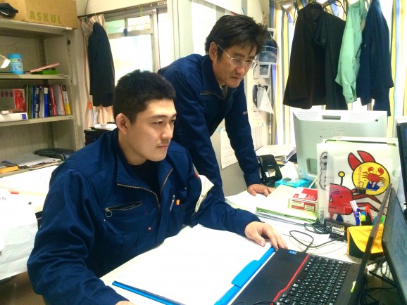 （二田さんと一緒に工事計画について確認する坂根さん。月に1回は二田さんや社長と、「最近どうや？うまくいってるか？」などと話し合う機会があるそうだ。）